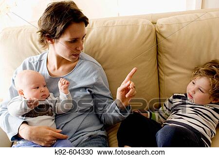 Mother holding a baby and disciplining a toddler. View Large Photo Image Stock Image - Mother holding a baby and disciplining a toddler.. Fotosearch
