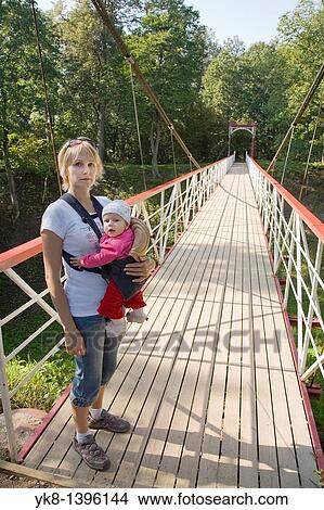 Picture - Mother Holding Baby in Carrier Sling on Bridge. Fotosearch