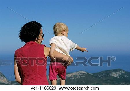Mother holding her baby girl while looking at the sea view. View Large Photo Image Stock Photo - Mother holding her baby girl while looking at the sea view.. Fotosearch