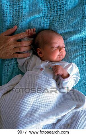 Mother holding the hand of her sleeping newborn View Large Photo Image Stock Photo - Mother holding the hand of her sleeping newborn. Fotosearch