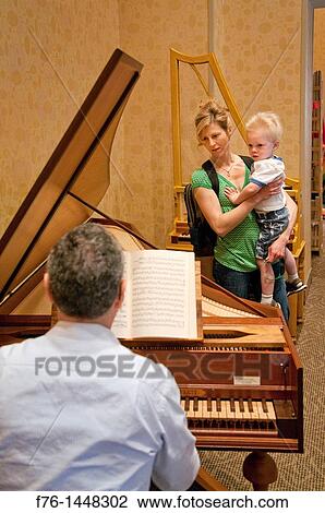 Mother, holding young son, listens to musician playing a custom, handmade harpsichord at the Boston Early Music Festival, Boston, Massachusetts, USA View Large Photo Image Stock Image - Mother, holding young son, listens to musician playing a custom, handmade harpsichord at the Boston Early Music Festival, Boston, Massachusetts, USA. Fotosearch