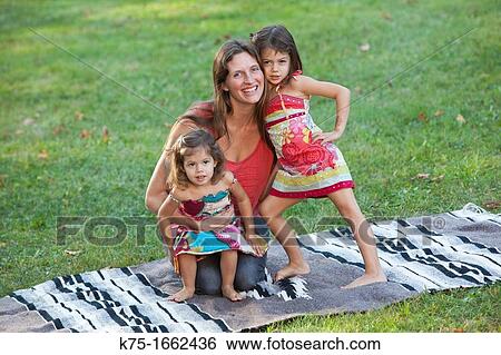 Mother hugging her two daughters on blanket View Large Photo Image Stock Photograph - Mother hugging her two daughters on blanket. Fotosearch