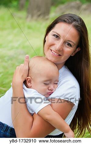 Stock Image - Mother in her 30s holding her baby boy of nine months. Fotosearch