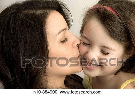 Stock Image - Mother kissing her young daughter. Model and Property Released.. Fotosearch