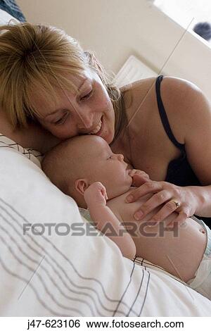 Mother lying on a bed with her 8 week old baby boy, he's just wearing a nappy View Large Photo Image Stock Photograph - Mother lying on a bed with her 8 week old baby boy, he's just wearing a nappy. Fotosearch