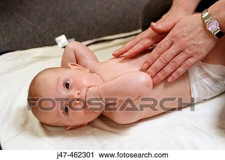 Stock Image - Mother massaging her babies tummy. Fotosearch