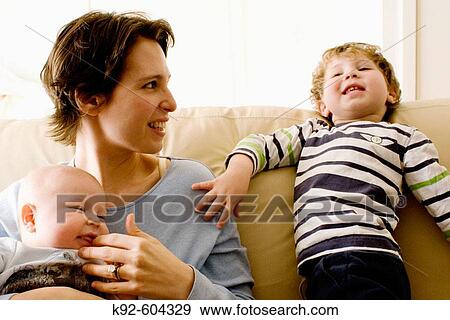 Stock Photo - Mother on couch with baby and toddler.. Fotosearch