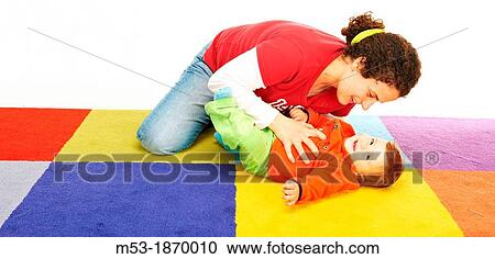 Mother Play with her ten months old baby girl on a colored carpet View Large Photo Image Stock Image - Mother Play with her ten months old baby girl on a colored carpet. Fotosearch