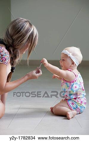 Mother showing a credit card to her daughter View Large Photo Image Picture - Mother showing a credit card to her daughter. Fotosearch