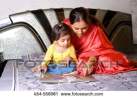 Mother teaching her daughter sitting on a bed. View Large Photo Image Stock Image - Mother teaching her daughter sitting on a bed.. Fotosearch