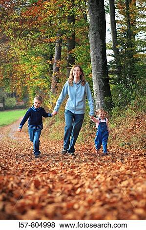 Mother with daughter and son running hand in hand on path full of leaves in fall, having fun and laughing, autumn foliage covering path in forest, autumn, fall, Zuerich, Switzerland View Large Photo Image Stock Photo - Mother with daughter and son running hand in hand on path full of leaves in fall, having fun and laughing, autumn foliage covering path in forest, autumn, fall, Zuerich, Switzerland. Fotosearch