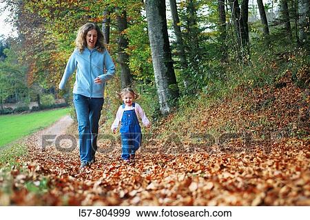 Mother with daughter running on path full of leaves in fall, having fun and laughing, autumn foliage covering path in forest, autumn, fall, Zuerich, Switzerland View Large Photo Image Stock Photo - Mother with daughter running on path full of leaves in fall, having fun and laughing, autumn foliage covering path in forest, autumn, fall, Zuerich, Switzerland. Fotosearch