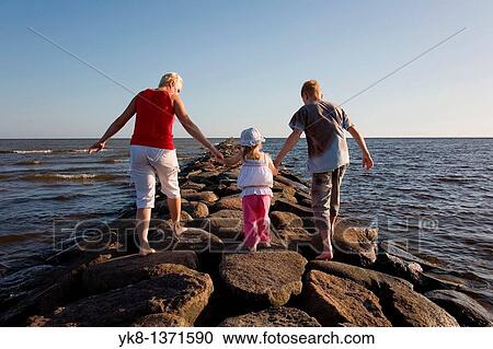Mother with Kid Girl and Teenage Boy Holding Hands Walking Away on P? rnu Pier by Sea, Estonia View Large Photo Image Stock Image - Mother with Kid Girl and Teenage Boy Holding Hands Walking Away on P? rnu Pier by Sea, Estonia. Fotosearch