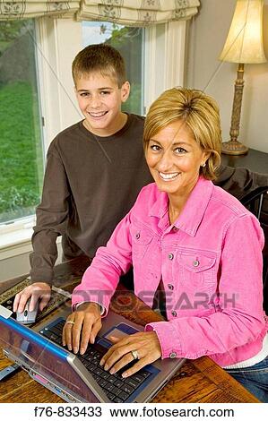 Mother working on laptop computer with adolescent son helping View Large Photo Image Stock Image - Mother working on laptop computer with adolescent son helping. Fotosearch
