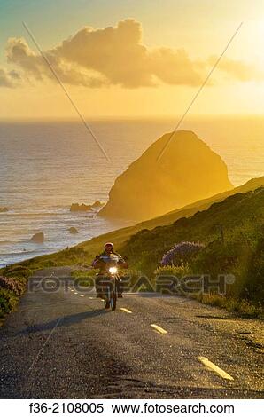 Stock Photography - Motorcycle at sunset on the Mattole Road, at Cape Mendocino, on the Lost Coast, California.. Fotosearch