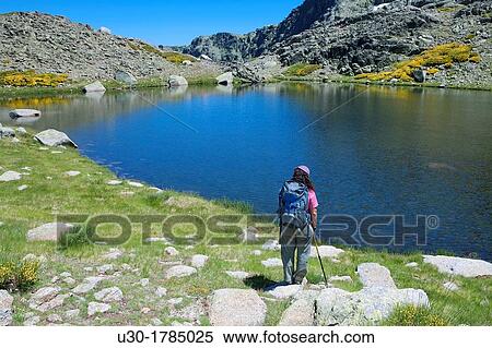 Stock Photography - Mountaineer walking down to Trampal Lagoons, in Sierra de Gredos Regional Park? vila Castilla y Le? n Spain. Fotosearch