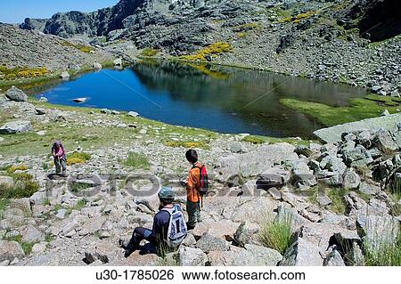Stock Photograph - Mountaineers walking from Trampal Lagoons, in Sierra de Gredos Regional Park? vila Castilla y Le? n Spain. Fotosearch