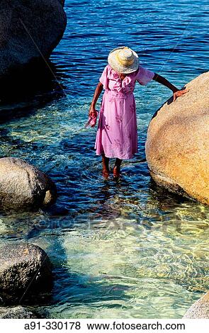 Mrs des Anges gathering shells. Anse Lazio beach and lagoon. Praslin Island. Seychelles View Large Photo Image Stock Photo - Mrs des Anges gathering shells. Anse Lazio beach and lagoon. Praslin Island. Seychelles. Fotosearch