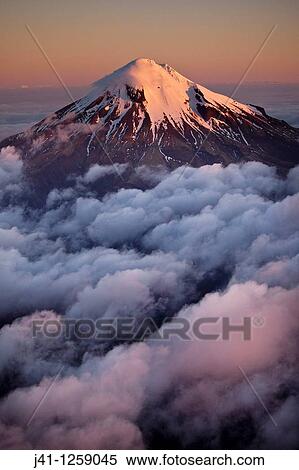 Stock Photography - Mt Egmont / Taranaki, western flanks of dormant volcano above evening cloud, sunset, Taranaki.. Fotosearch