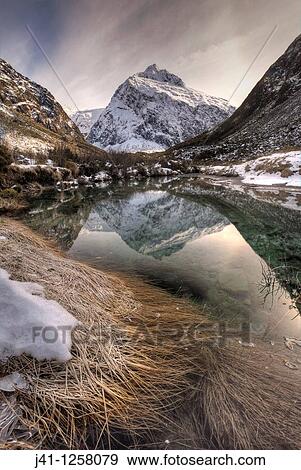 Stock Photo - Mt Talbot, winter reflection with ice halo in sky, Hollyford valley, Fiordland National Park, World Heritage site.. Fotosearch