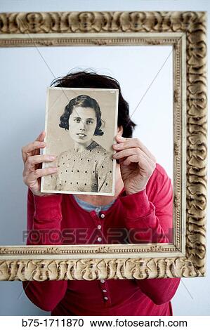 Mujer joven dentro de un marco dorado con retrato antiguo en las manos tapandole la cara, Young woman in a gold frame with old picture in her hands covering her face, View Large Photo Image Stock Image - Mujer joven dentro de un marco dorado con retrato antiguo en las manos tapandole la cara, Young woman in a gold frame with old picture in her hands covering her face,. Fotosearch