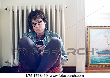 Mujer joven sentada en el suelo llamando por telefono, Young woman sitting on the floor calling by phone View Large Photo Image Stock Photo - Mujer joven sentada en el suelo llamando por telefono, Young woman sitting on the floor calling by phone. Fotosearch