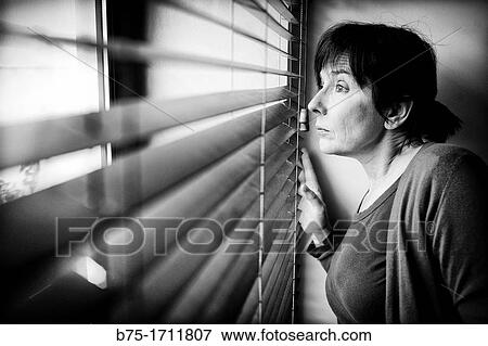 Stock Photo - mujer mirando a traves de la ventana, woman looking through the window. Fotosearch