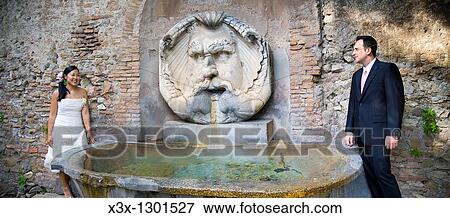 Multi-ethnic bride and groom standing near fountain in Piazza Illiria, Rome, Italy View Large Photo Image Stock Photo - Multi-ethnic bride and groom standing near fountain in Piazza Illiria, Rome, Italy. Fotosearch