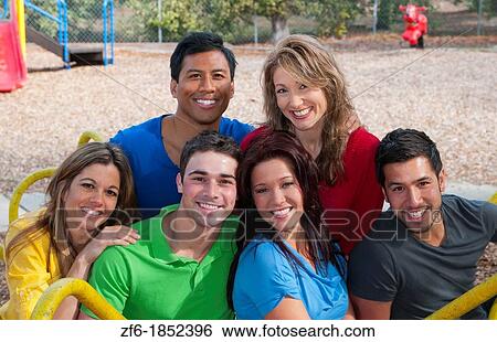 Multi ethnic friends aged 20s in playground laughing and sharing fun in spinning wheel of colors together View Large Photo Image Stock Photograph - Multi ethnic friends aged 20s in playground laughing and sharing fun in spinning wheel of colors together. Fotosearch