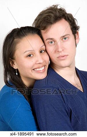 Stock Image - Multicultural couple portrait hugging White background. Fotosearch