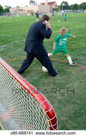 Multitasking dad in business suit talking on cell phone and playing soccer Carondelet Field Expo School St Paul Minnesota USA View Large Photo Image Stock Image - Multitasking dad in business suit talking on cell phone and playing soccer Carondelet Field Expo School St Paul Minnesota USA. Fotosearch