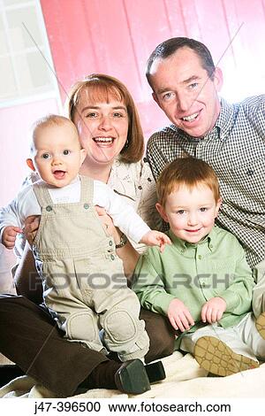 Mum and dad sitting with their two sons, ages 3 and 1, all smiling into camera View Large Photo Image Stock Image - Mum and dad sitting with their two sons, ages 3 and 1, all smiling into camera. Fotosearch