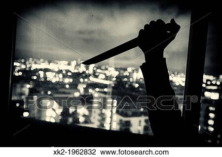 Stock Image - Murder in a kitchen using knife at night. Fotosearch