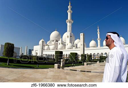 Stock Image - Muslimm Emirates man in white dishelash at the beautiful white Sheikh Zayed Grand Mosque in Abu Dhabi in the UAE the worlds 8th largest Muslim mosque in the world.. Fotosearch