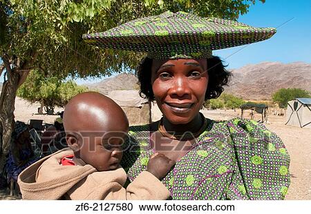 Namibia Africa Northern Desert colorful Herero tribe women in plaid dress and hat with child and traditional costume in Tomakas in Puros Conservancy remote village. View Large Photo Image Stock Image - Namibia Africa Northern Desert colorful Herero tribe women in plaid dress and hat with child and traditional costume in Tomakas in Puros Conservancy remote village.. Fotosearch