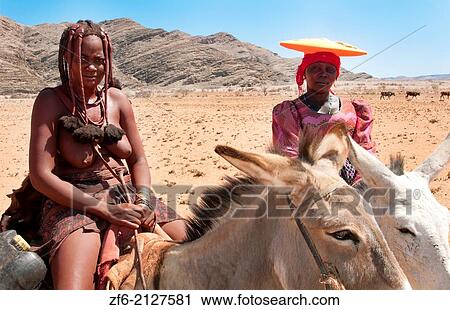 Namibia Africa Northern Desert colorful Herero tribe woman and Himba woman riding mules herding goats in Tomakas in Puros Conservancy remote farming. View Large Photo Image Stock Image - Namibia Africa Northern Desert colorful Herero tribe woman and Himba woman riding mules herding goats in Tomakas in Puros Conservancy remote farming.. Fotosearch