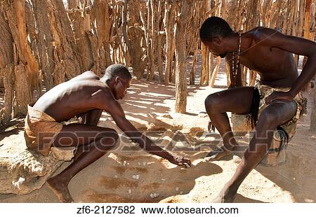 Stock Image - Namibia Africa remote Damara Tribe in Damaraland boys playing traditional game called llgus in native village.. Fotosearch