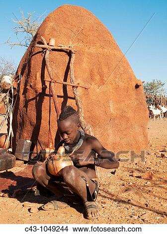 Namibia - Himba boy with the typical single plait hairstyle of the young boys repairing a pot used for butter fat In a village near the Epupa Falls Kaokoland, Kunene region, northern Namibia View Large Photo Image Picture - Namibia - Himba boy with the typical single plait hairstyle of the young boys repairing a pot used for butter fat In a village near the Epupa Falls Kaokoland, Kunene region, northern Namibia. Fotosearch