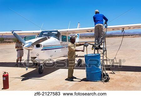Stock Image - Namibia Namib Desert refueling plane in the Hartmann Berge Marienflub sand remote landing strip with workers pumping manually fuel gas.. Fotosearch