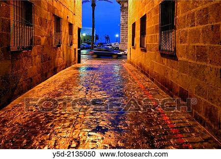 Stock Image - narrow street of Cadiz by night after rain, Andalusia, Spain.. Fotosearch