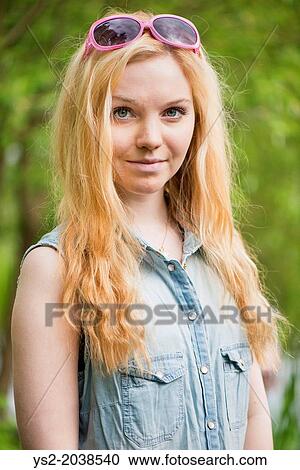 Stock Image - Nature scene with one young attractive woman standing in a park.. Fotosearch