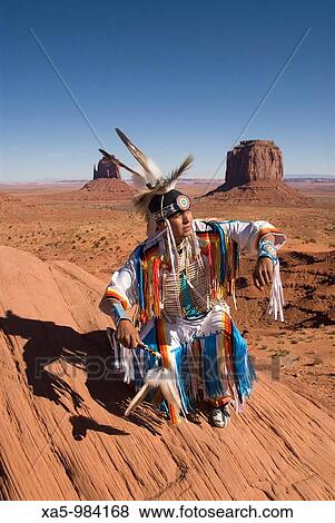 Navajo Indian dressed in a traditional costume, in background is Merrick Butte right and East Mitten Butte left, Monument Valley Navajo Tribal Park, Arizona, USA View Large Photo Image Stock Photo - Navajo Indian dressed in a traditional costume, in background is Merrick Butte right and East Mitten Butte left, Monument Valley Navajo Tribal Park, Arizona, USA. Fotosearch