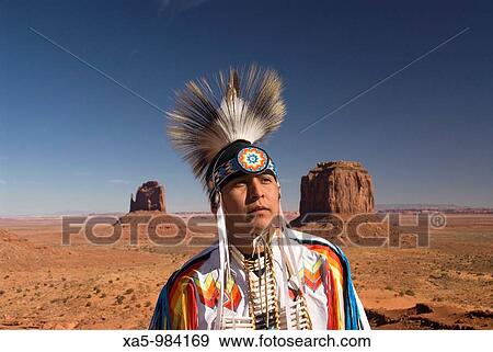Navajo Indian dressed in a traditional costume, in background is Merrick Butte right and East Mitten Butte left, Monument Valley Navajo Tribal Park, Arizona, USA View Large Photo Image Stock Photo - Navajo Indian dressed in a traditional costume, in background is Merrick Butte right and East Mitten Butte left, Monument Valley Navajo Tribal Park, Arizona, USA. Fotosearch