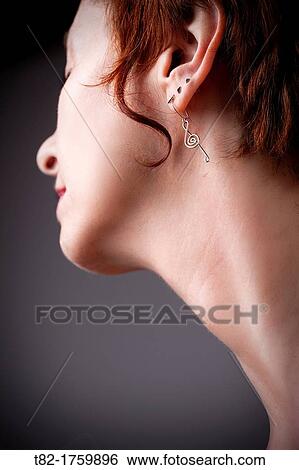 Stock Photograph - neck detail and profile of young woman with short hair and red and pending musical clef. Fotosearch