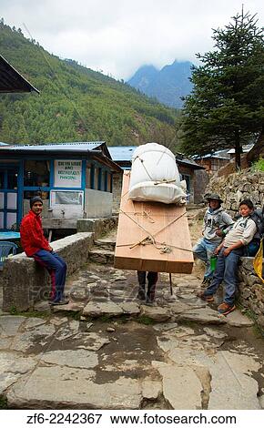 Nepal Himalayas Porter carrying massive load through the streets of Phak Ding Solukhumbu remote Mt Everest 55 56. View Large Photo Image Stock Photo - Nepal Himalayas Porter carrying massive load through the streets of Phak Ding Solukhumbu remote Mt Everest 55 56.. Fotosearch
