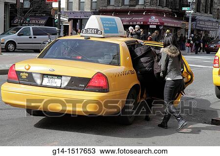 Stock Image - New York, New York City, NYC, Lower, Manhattan, SoHo, Spring Street, taxi, cab, boarding, woman, passenger, street scene, public transportation, car, fare, yellow,. Fotosearch