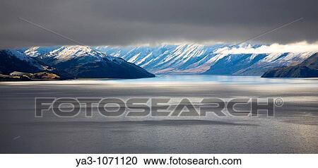 New Zealand, Otago, Lake Hawea The Southern Alps revealed through a small gap between dense snow clouds and the surface of Lake Hawea View Large Photo Image Stock Image - New Zealand, Otago, Lake Hawea The Southern Alps revealed through a small gap between dense snow clouds and the surface of Lake Hawea. Fotosearch