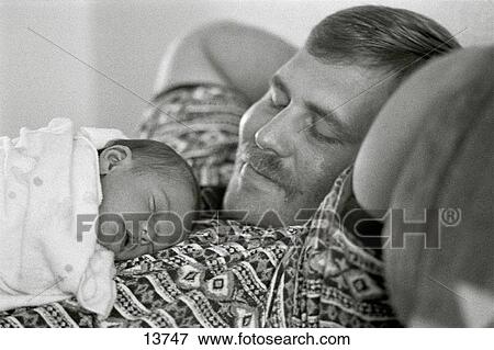 Stock Photo - Newborn baby sleeps upon father's chest. Fotosearch