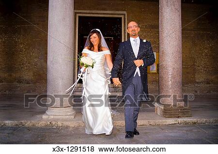 Stock Photo - Newlyweds hit by rice at church exit after the wedding. Fotosearch