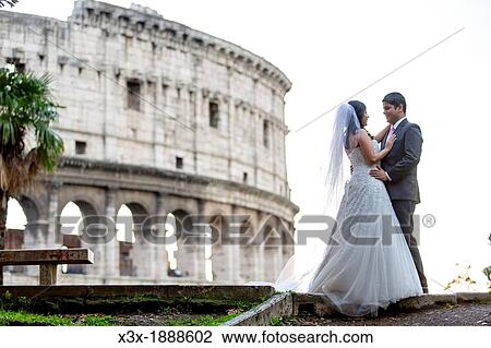 Stock Image - Newlyweds in front of the roman Colosseum in Rome Italy. Fotosearch